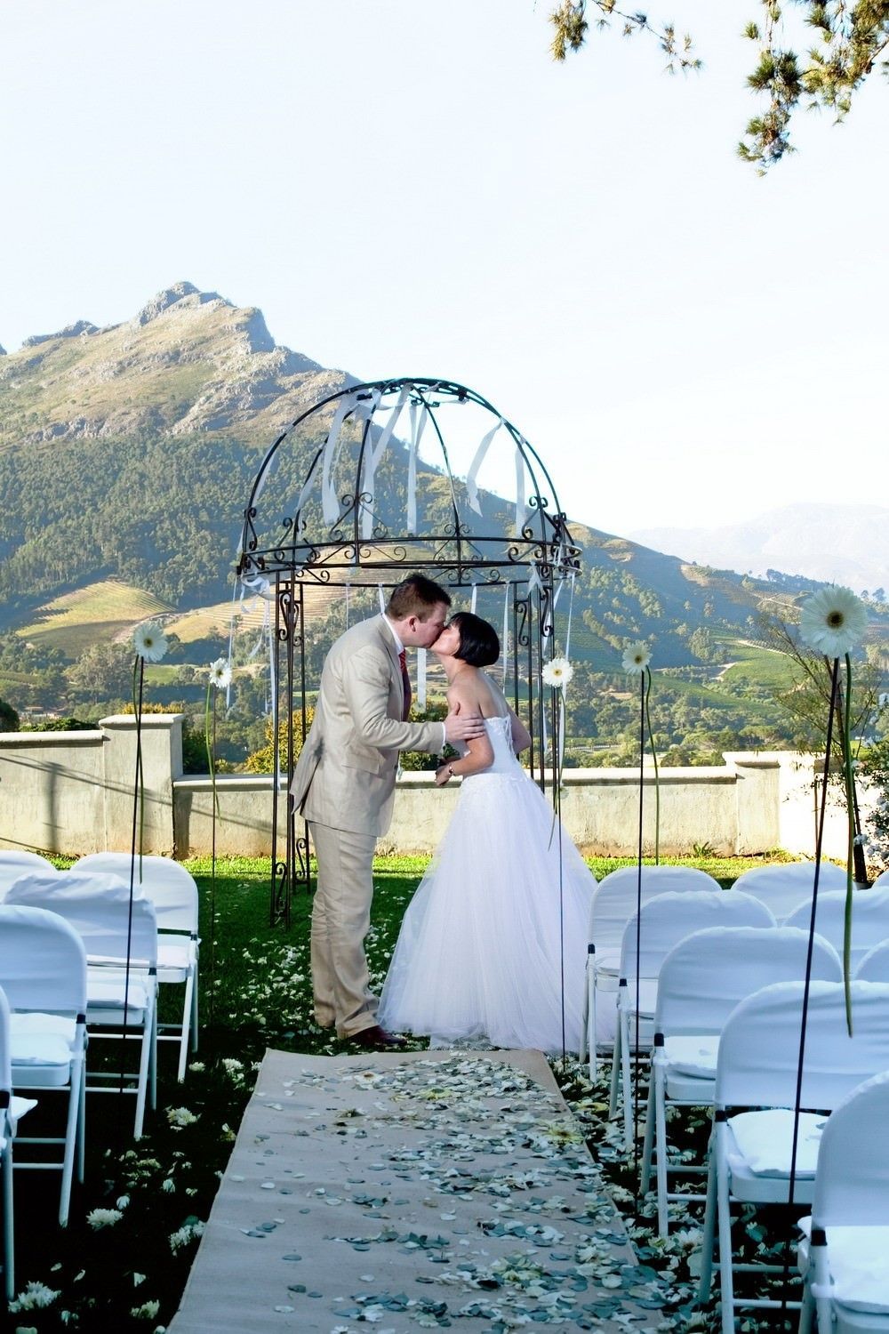 A bride and groom kissing at their wedding ceremony with mountains in the background