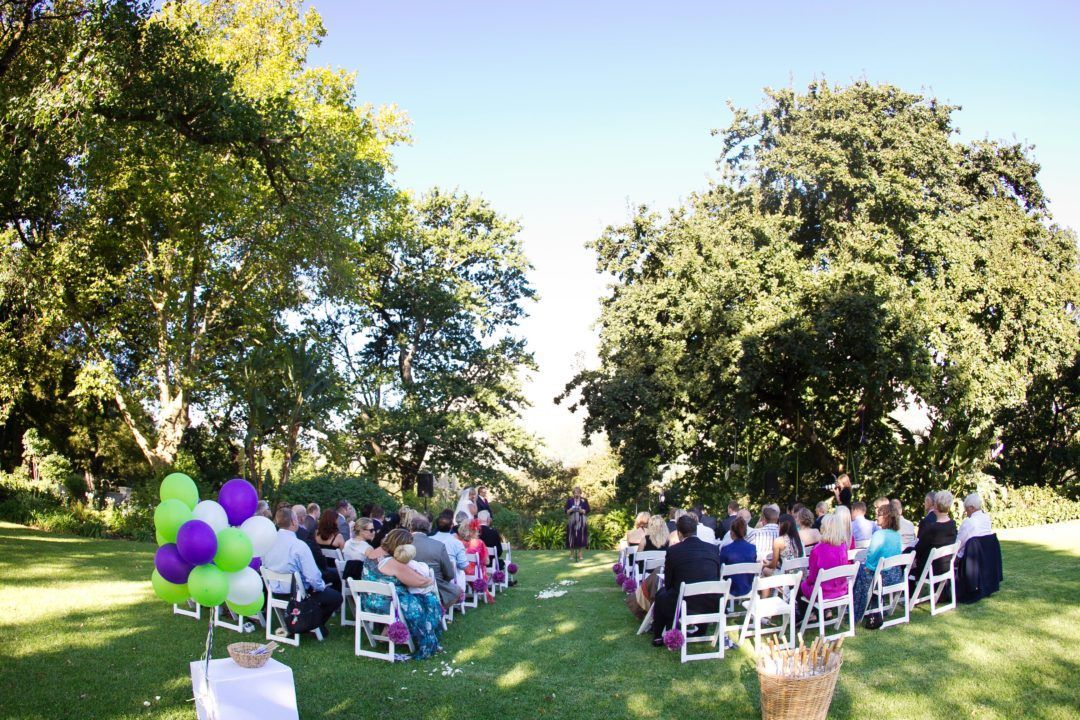 A group of people are sitting in chairs in a field at a wedding ceremony.