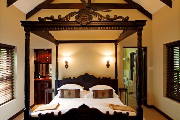 A bedroom with a four poster bed and a ceiling fan