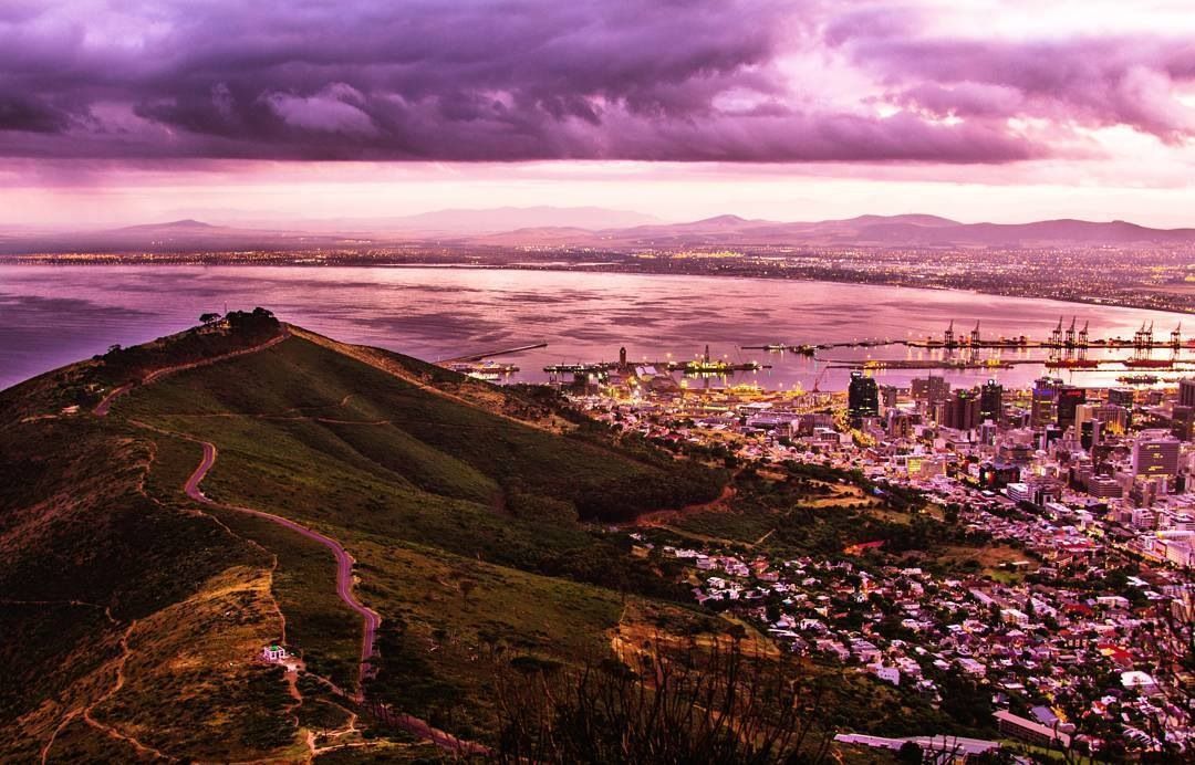 A view of a city from the top of a hill at sunset.