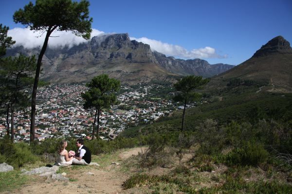 A couple sitting on top of a hill overlooking a city