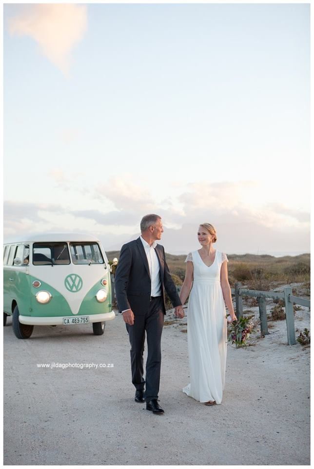 A bride and groom are holding hands in front of a vw van.