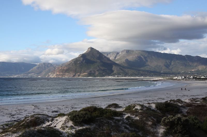 A beach with mountains in the background and a cloudy sky