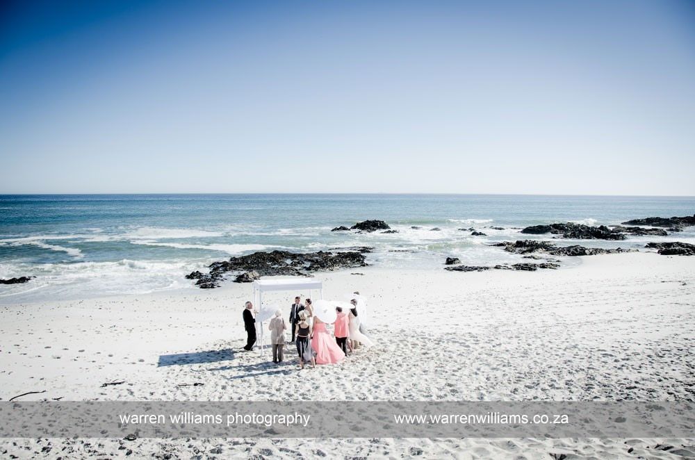 A group of people are standing on a beach near the ocean.