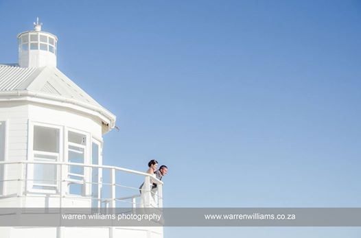 A bride and groom standing on top of a white building