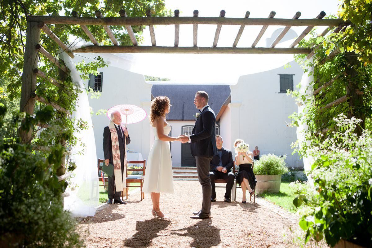 A bride and groom are holding hands during their wedding ceremony