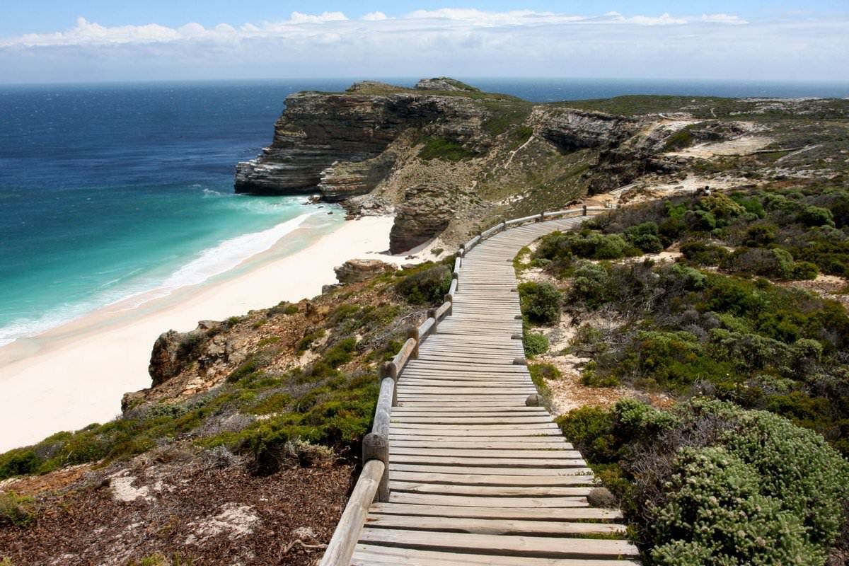 A wooden walkway leading to a beach on a cliff overlooking the ocean