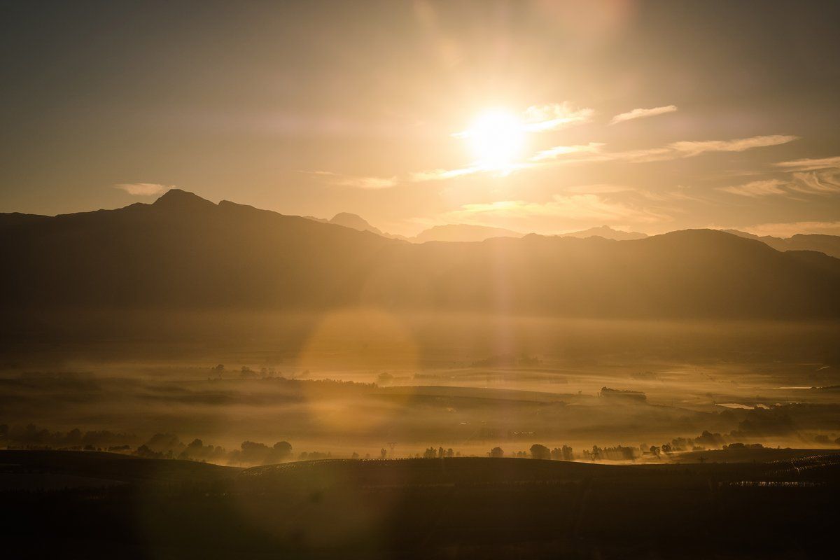 The sun is setting over a lake with mountains in the background.