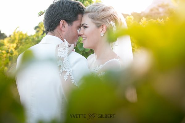 A bride and groom are looking into each other 's eyes.