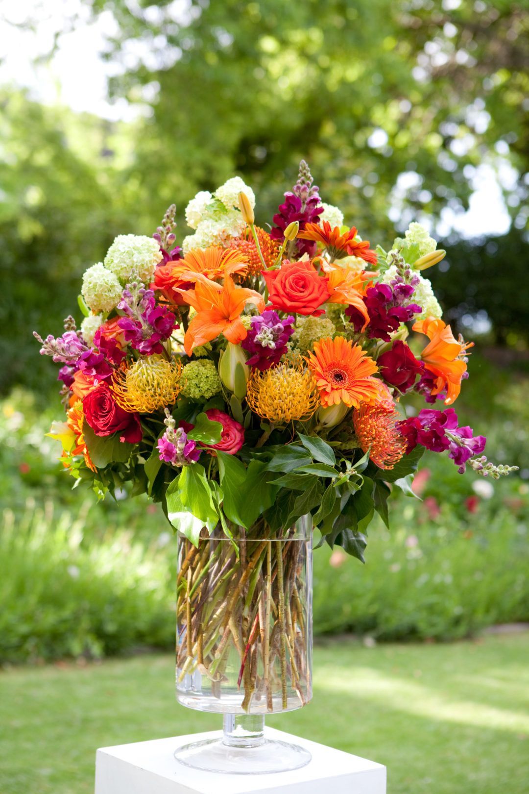 A vase filled with colorful flowers is sitting on top of a white block.