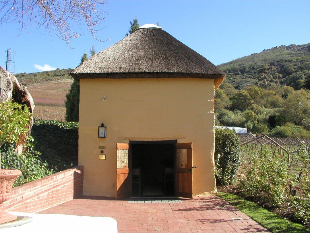 A small yellow building with a thatched roof
