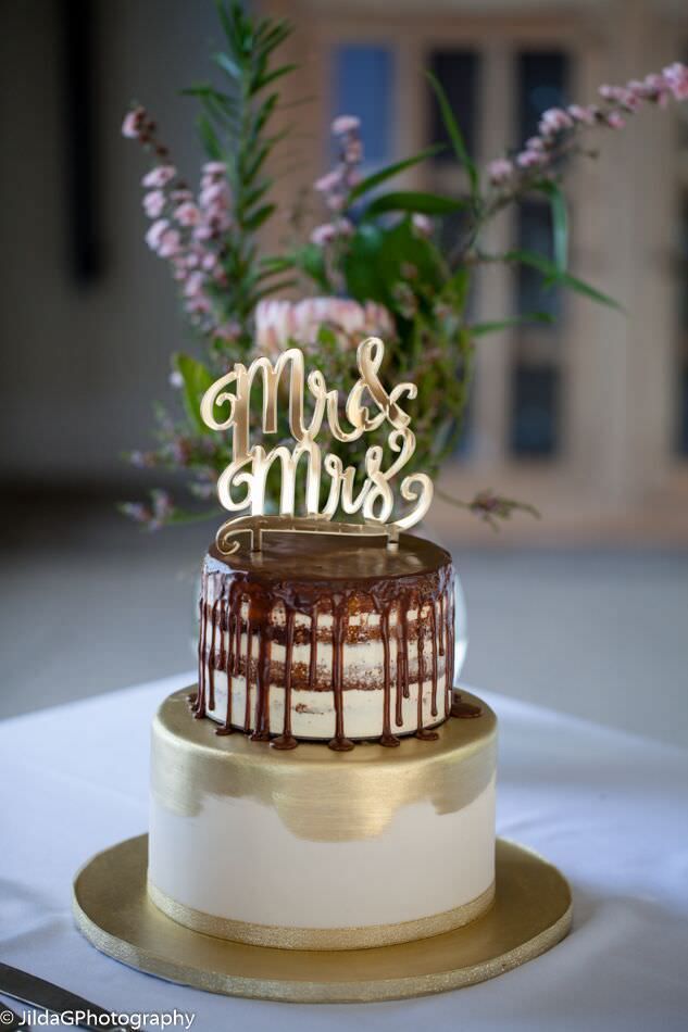 A wedding cake with a mr. and mrs. cake topper is sitting on a table.