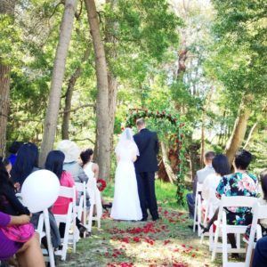 A bride and groom are walking down the aisle at a wedding ceremony in the woods.