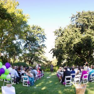 A group of people are sitting in white chairs at a wedding ceremony.