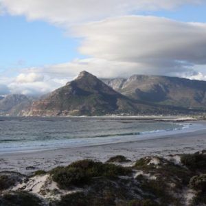 A beach with mountains in the background and a cloudy sky