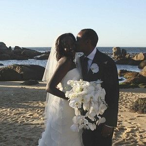 A bride and groom are kissing on the beach.