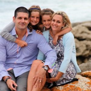 A family posing for a picture while sitting on a rock