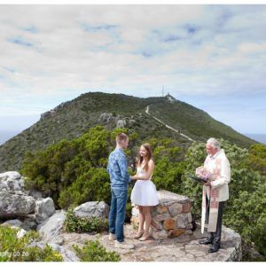A bride and groom are getting married on top of a mountain