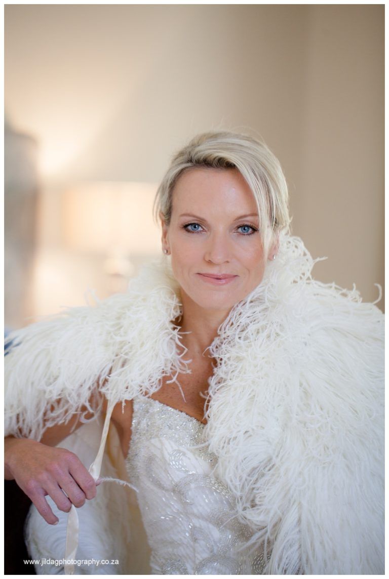A woman in a wedding dress is wearing a white feathered cape.