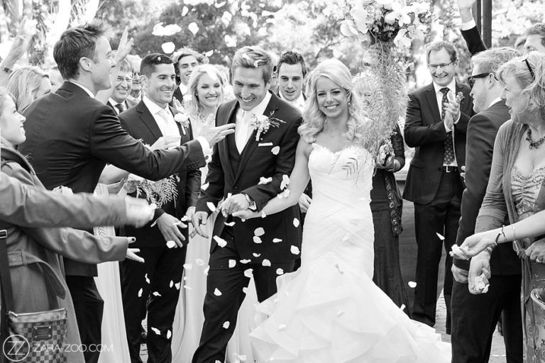 A black and white photo of a bride and groom being showered with confetti