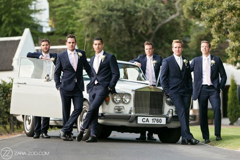 A group of men in suits standing next to a white car.