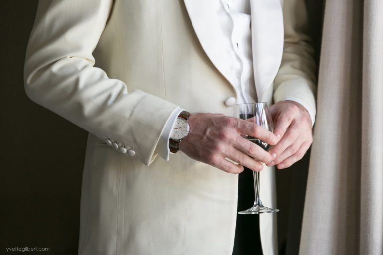 A man in a tuxedo is holding a glass of wine.