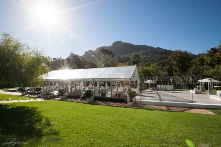 A large white tent is sitting in the middle of a lush green field.