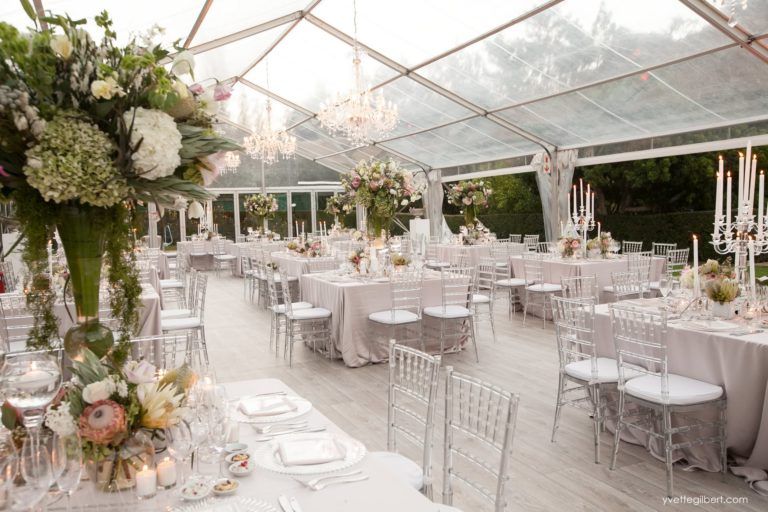 A large tent with tables and chairs set up for a wedding reception.