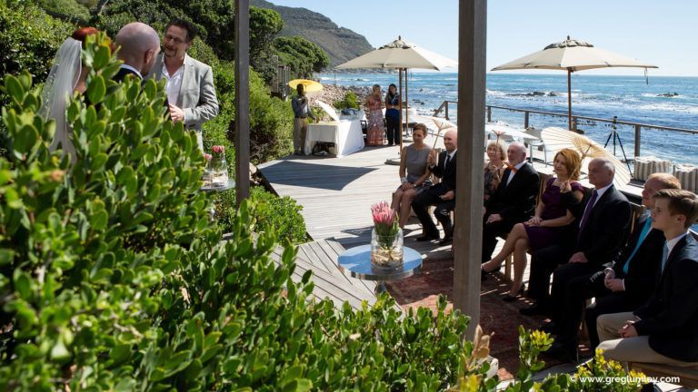 A bride and groom are getting married in front of the ocean.