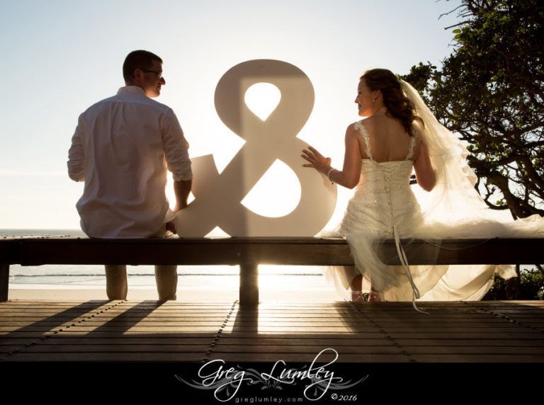A bride and groom are sitting on a bench in front of a large number 8
