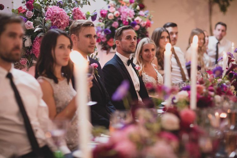 A group of people are sitting at a long table with candles and flowers.