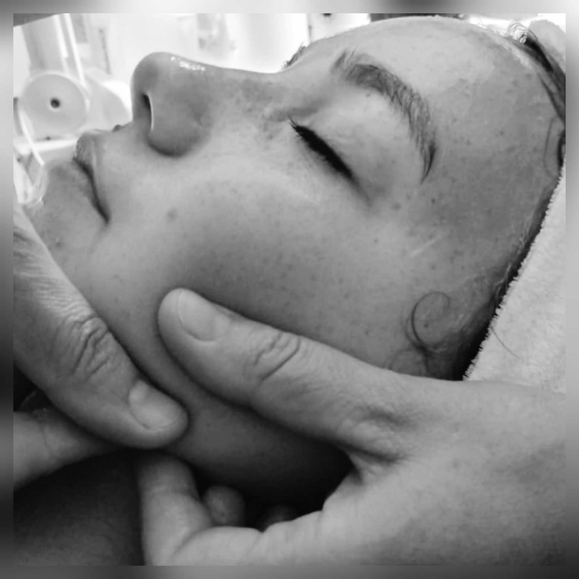 Een paar handen voert een gezichtsmassage uit op iemand die een spabehandeling ondergaat.