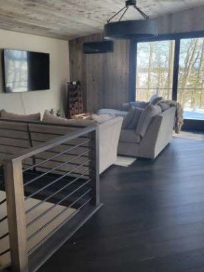 Living room with dark wood floors, large windows, and a gray couch.