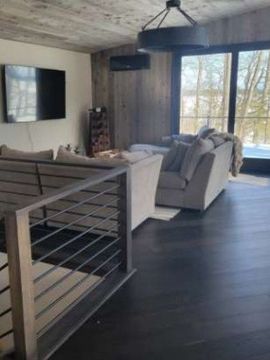 Living room with dark wood floors, large windows, and a gray couch.