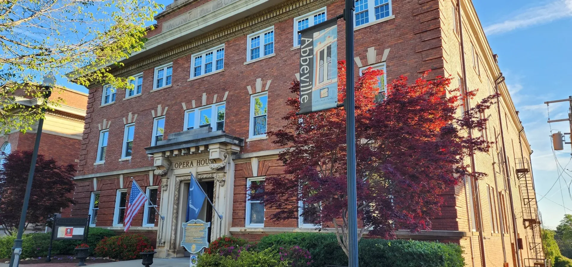 A large brick building with a lot of windows and trees in front of it.