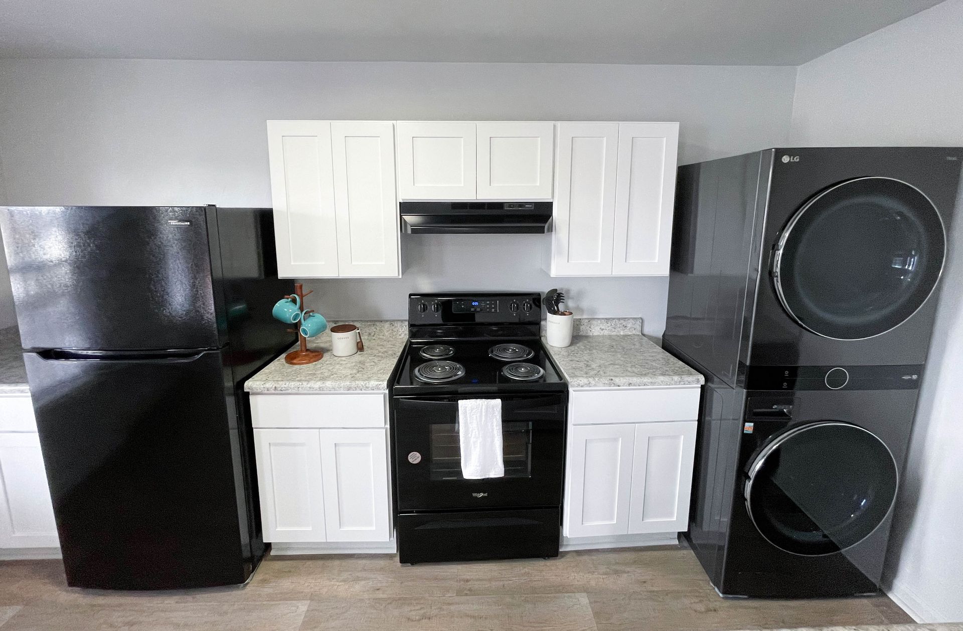 A kitchen with a refrigerator , stove , washer and dryer stacked on top of each other.