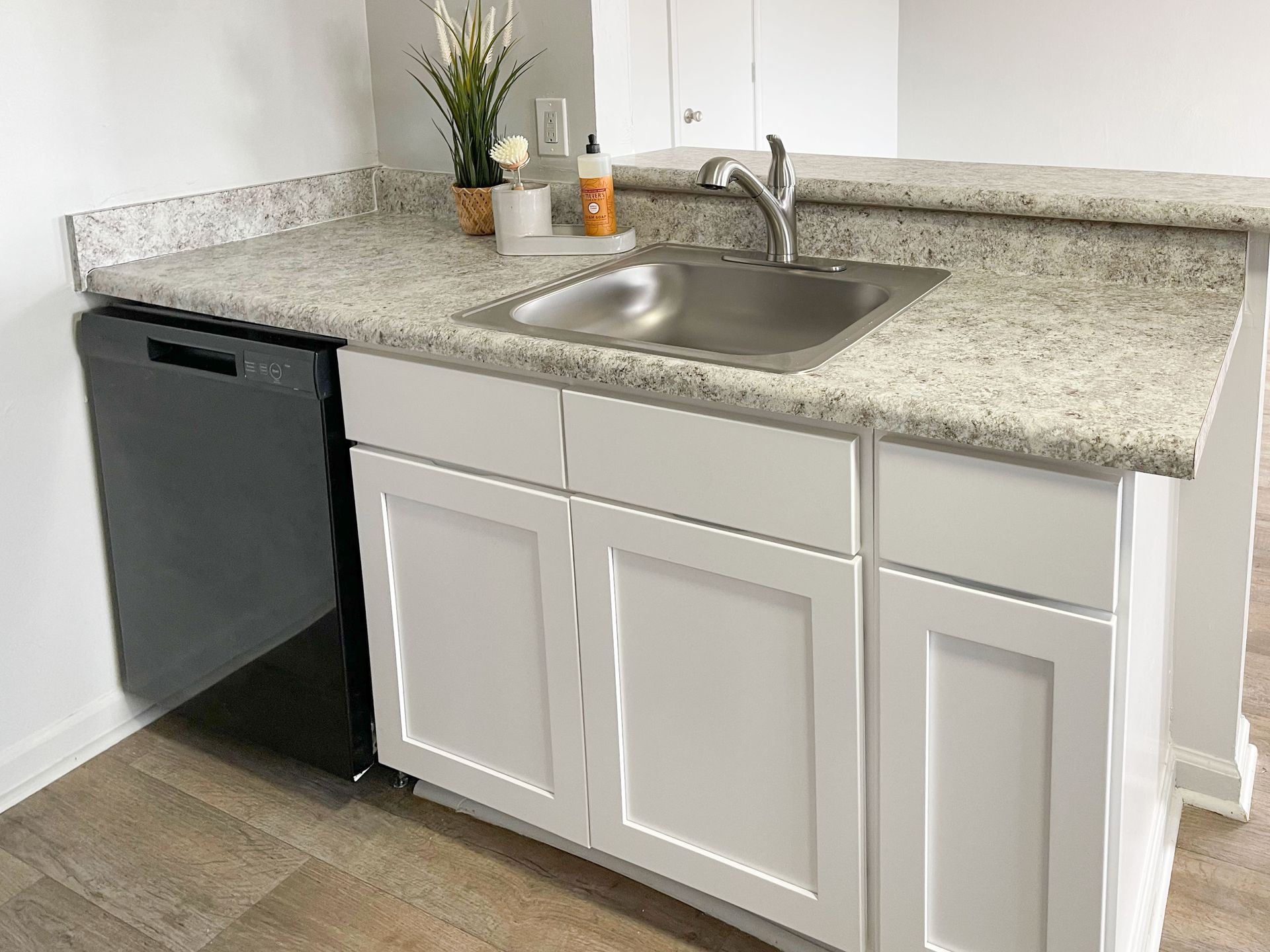 A kitchen with a sink , cabinets , and a dishwasher.