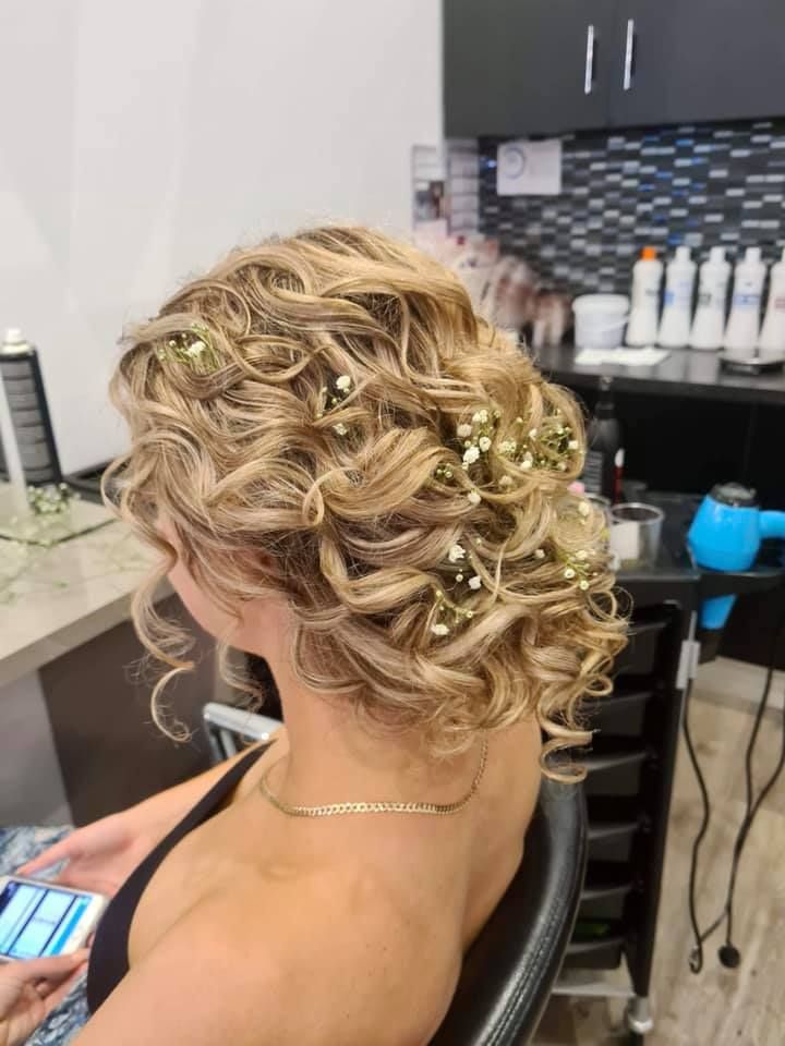 Woman With Blonde Curly Hair Styled Up, Adorned With Small White Flowers — Artistry Of Hair in Redlynch, QLD