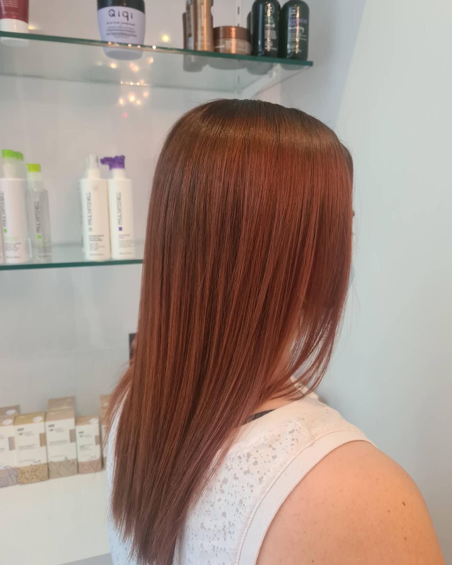 Person Straightening Reddish-brown Hair With a Black Flat Iron — Artistry Of Hair in Redlynch, QLD