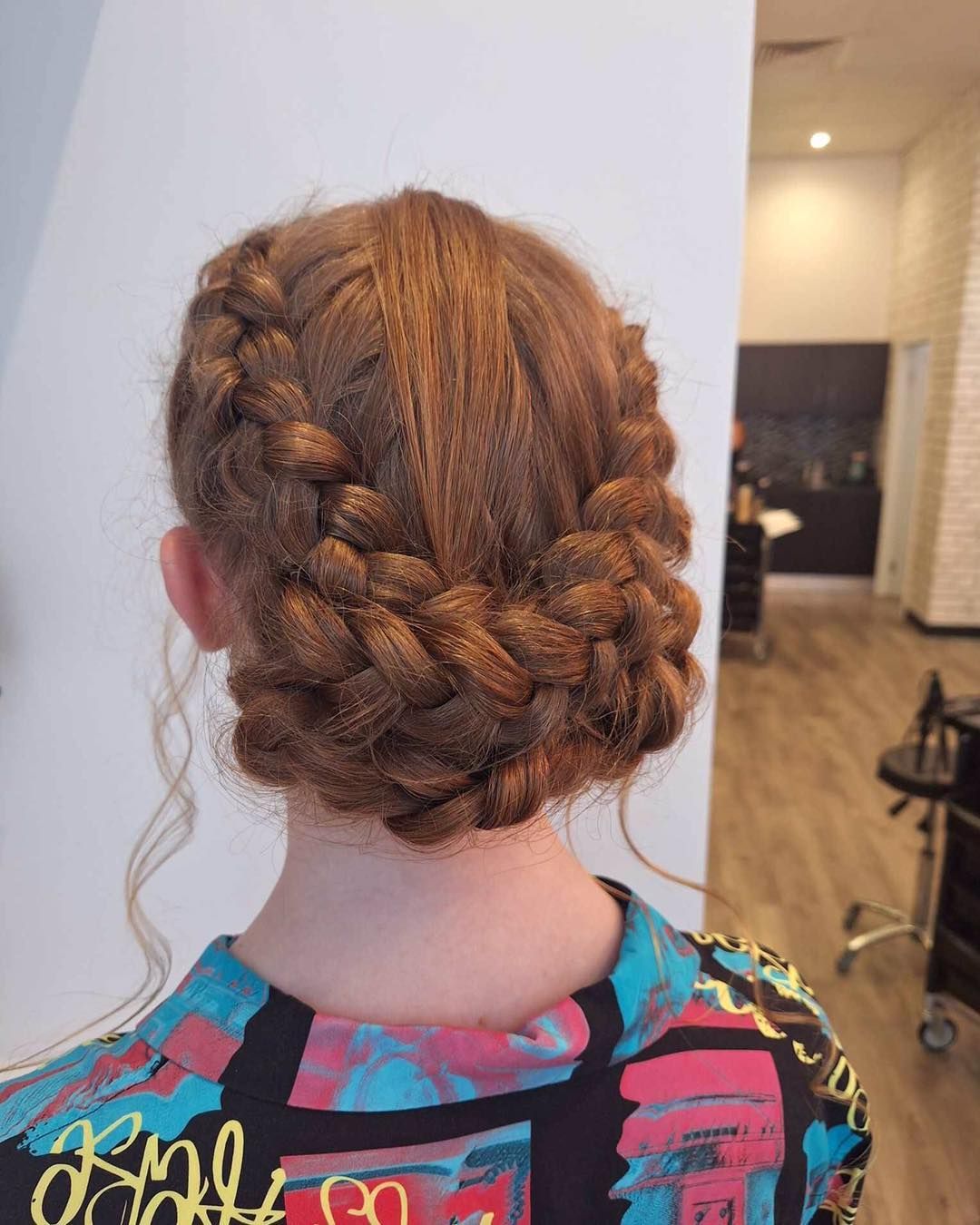 Person With Auburn Hair in Braided Updo Hairstyle, Wearing a Patterned Top, in a Salon — Artistry Of Hair in Redlynch, QLD