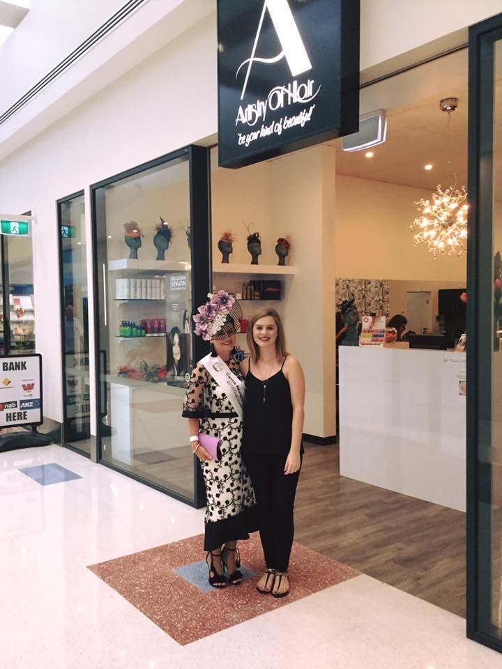 Two Women Stand Outside a Shop. One Wears a Dress and Hat, the Other a Jumpsuit — Artistry Of Hair in Redlynch, QLD