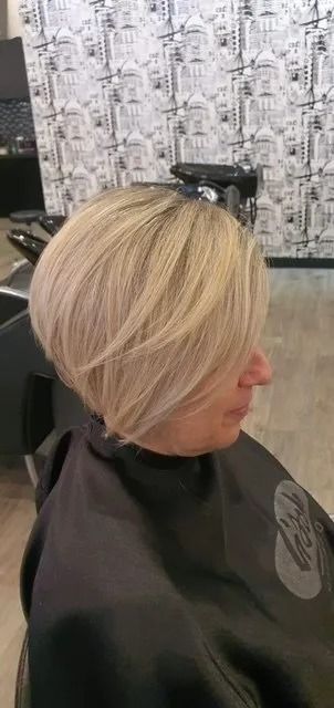 Woman With Short, Layered Blonde Hair in a Salon, Wearing a Black Cape — Artistry Of Hair in Redlynch, QLD