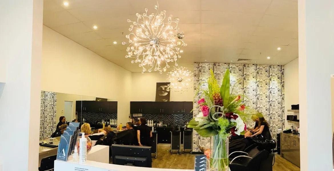 Hair Salon Interior With Stylists, Mirrors, and Floral Display — Artistry Of Hair in Redlynch, QLD