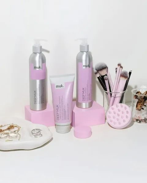 Pink Muk Hair Products With Accessories on a White Surface and Pink Blocks — Artistry Of Hair in Redlynch, QLD
