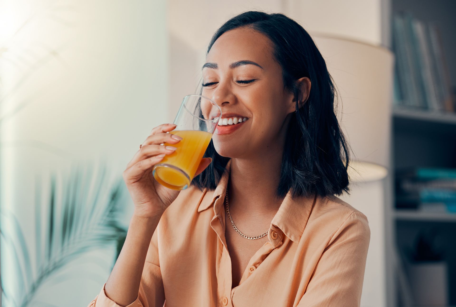 Woman smiles while drinking orange juice from a glass Woman smiles while drinking orange juice from a glass