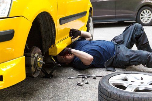Brake Repair & Replacement — Man Fixing Car Brakes in Boone, IA