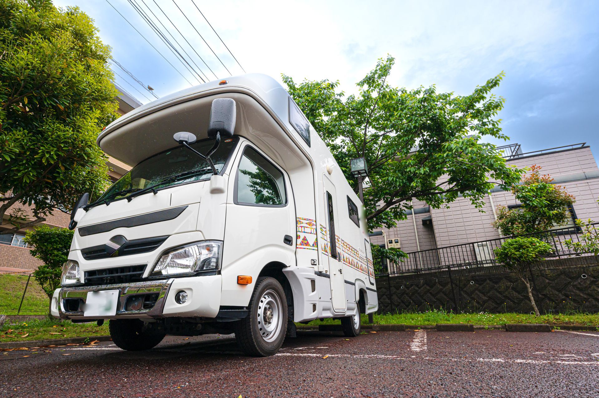 A white rv is parked on the side of the road in front of a building.