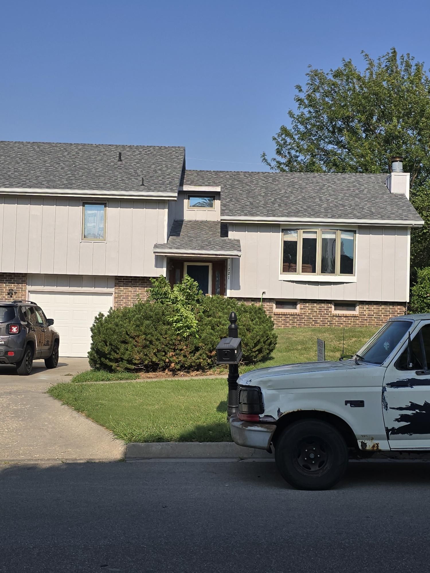 Two-story house with light gray siding, white garage door, and a white pickup truck parked in front.