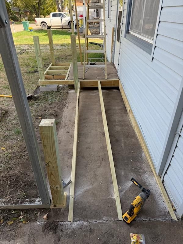Construction of a wooden ramp and landing. Wooden beams frame a new ramp along a gray house.