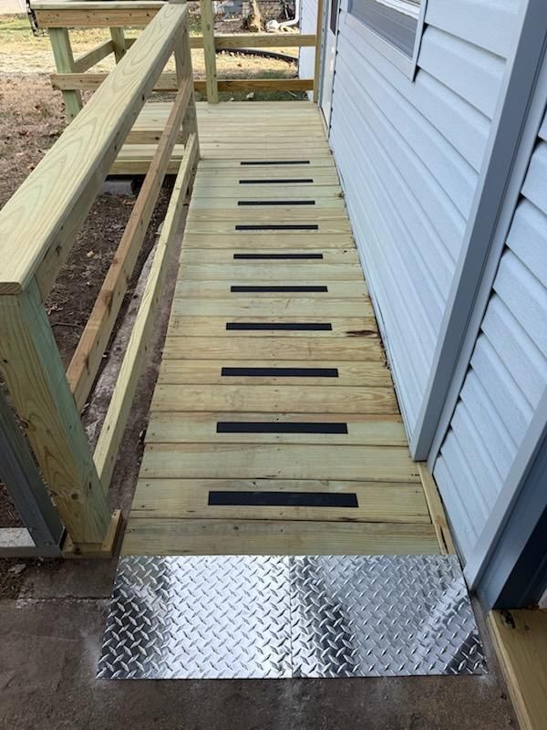Wooden wheelchair ramp with black non-slip strips and metal threshold.